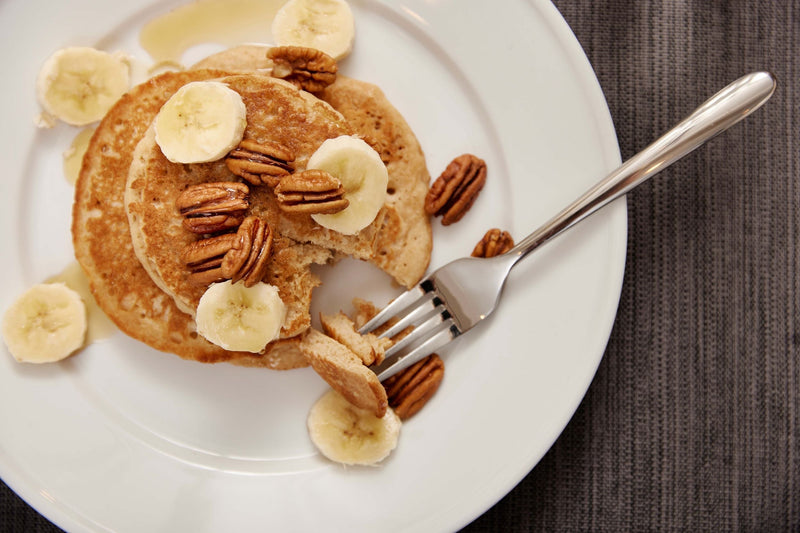 A stack of Step One Foods pancakes topped with bananas and pecans
