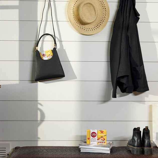 2 yellow boxes of Anytime sprinkle, one in a black hanging purse and one on top of a stack of books