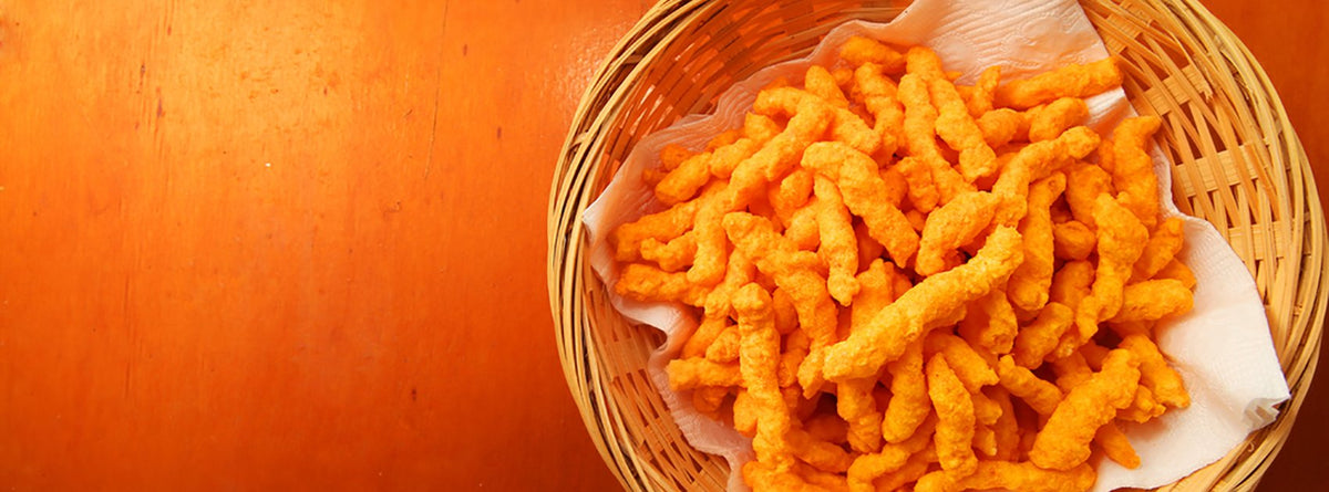 Cheetos in a wicker basket on a white napkin on a wooden table