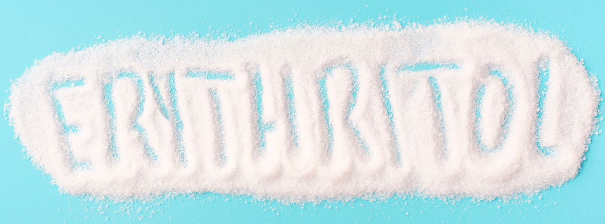 A spoonful of white erythritol sweetener beside processed diet foods