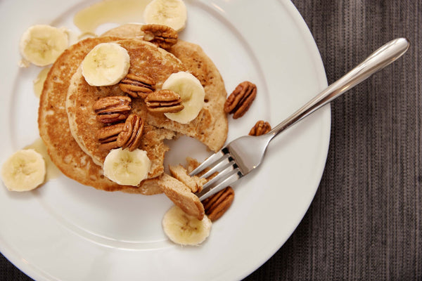 A stack of Step One Foods pancakes topped with bananas and pecans