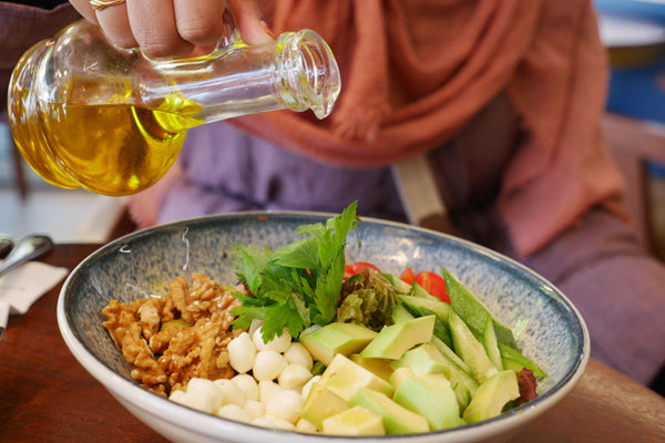 A plate of cholesterol-lowering foods including walnuts, vegetables, and olive oil