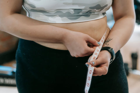 Healthcare provider measuring a patient's waist circumference with a tape measure